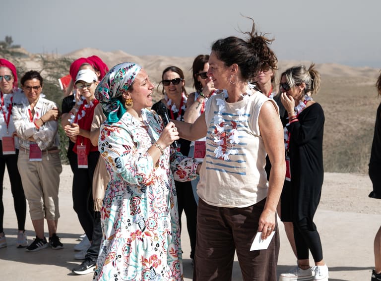 An educator speaking with a participant in front of the group in the desert