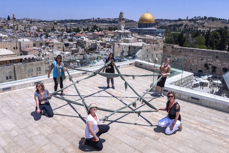 Women holding a large Star of David on a rooftop above the Old City