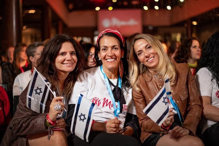 Women holding Israeli flags together at a Momentum gathering