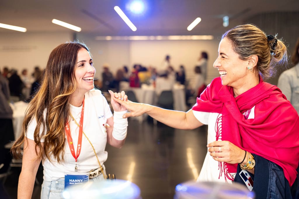 Two Momentum mothers laughing and holding hands during a gathering in Israel